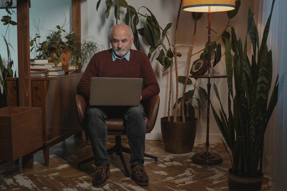 Usměvavá žena středního věku pracující na notebooku v příjemném prostředí.